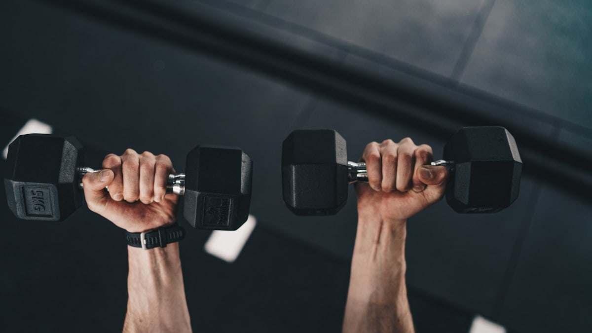 a man lifting two dumbs in a gym